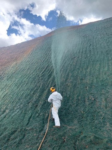 Homem vestindo branco jateando Hidrossemeadura em talude de alto grau de inclinação